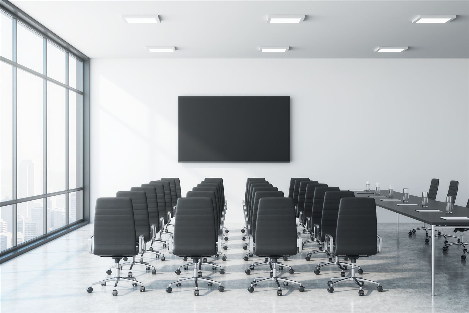 A bright meeting room reset with rows of empty chairs, water glasses and notepads on a side table
